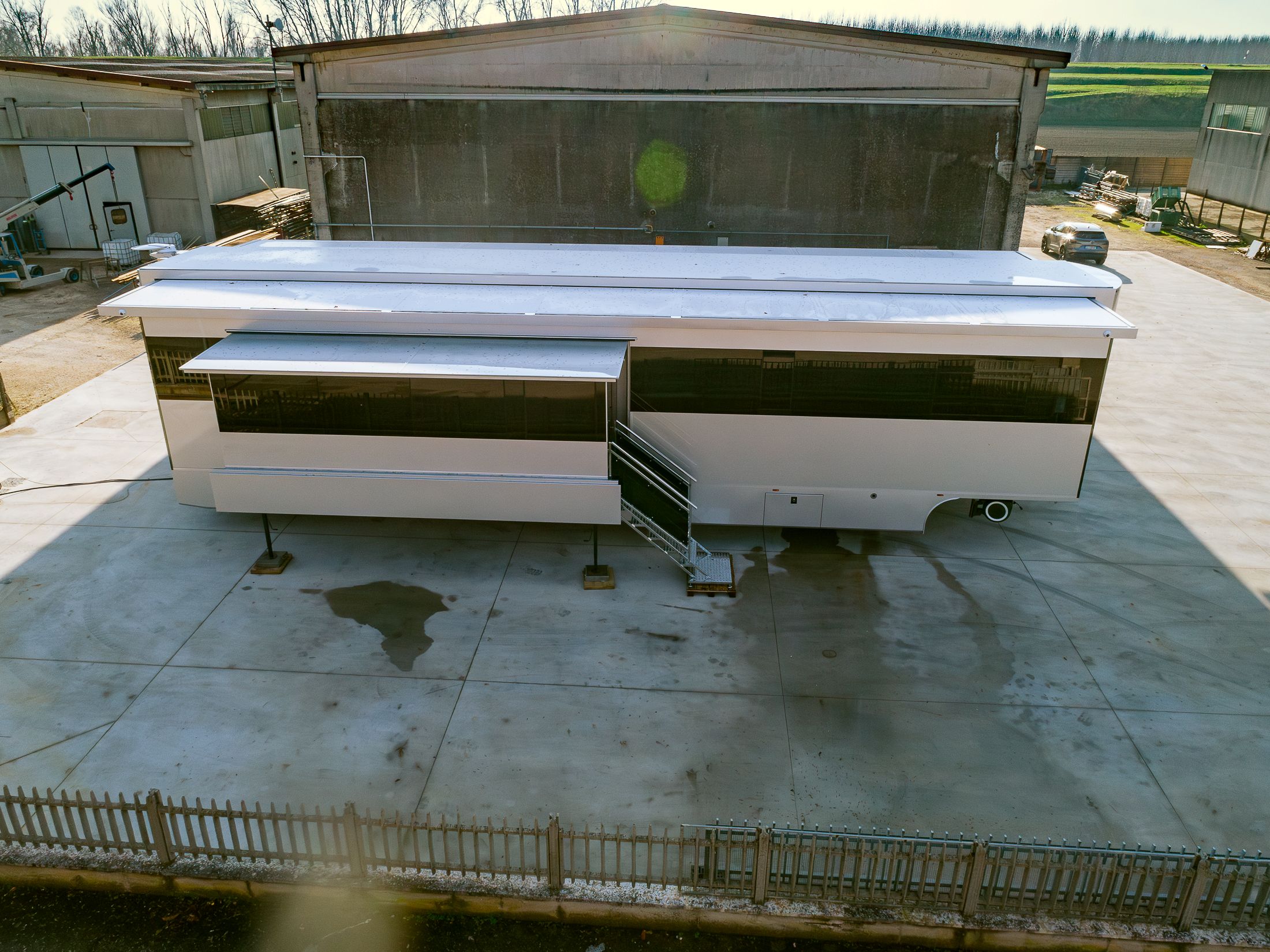 Vista aerea frontale di un living trailer completo, con scaletta di accesso estesa