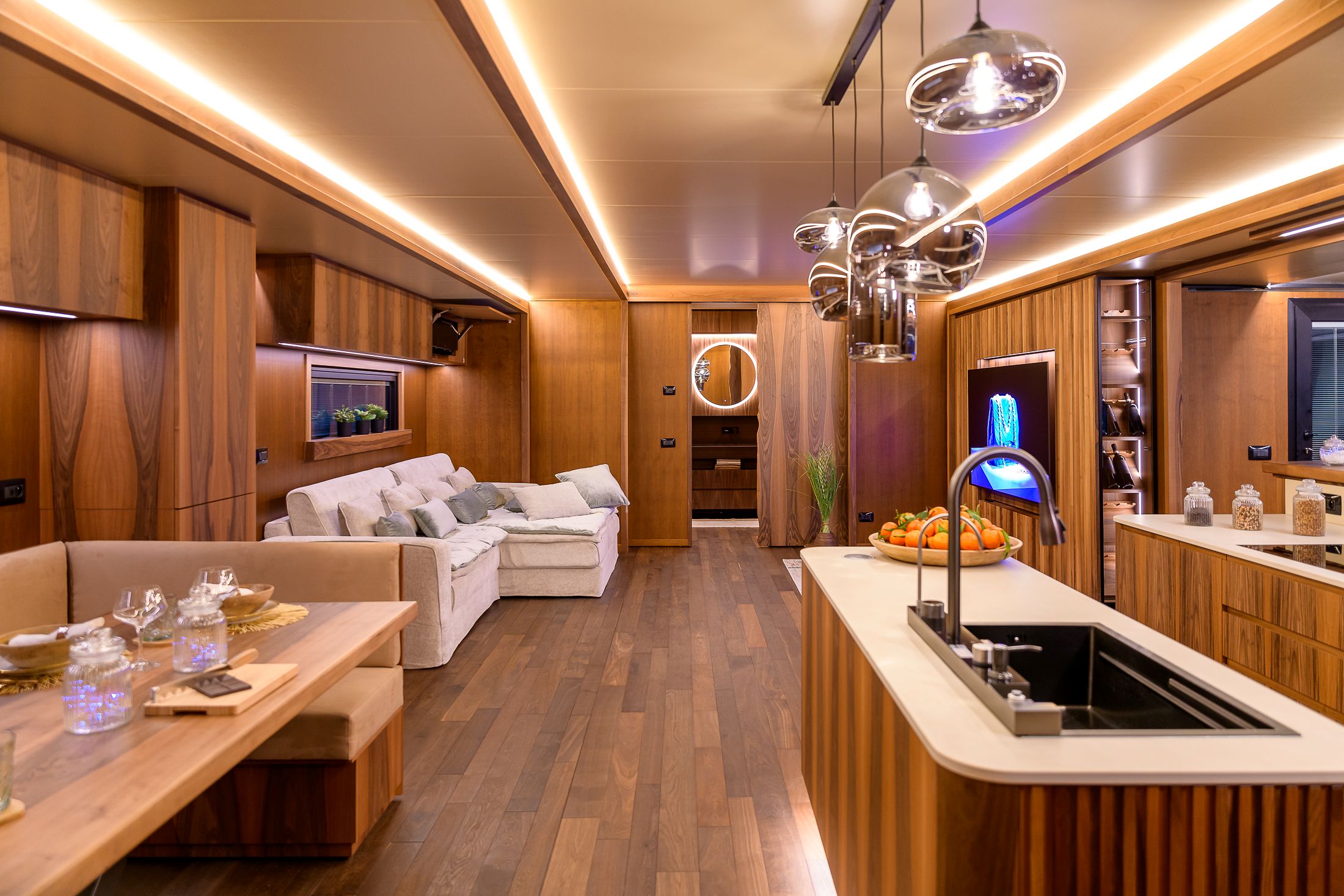 Interno di un living trailer con soggiorno, cucina a isola e illuminazione a LED