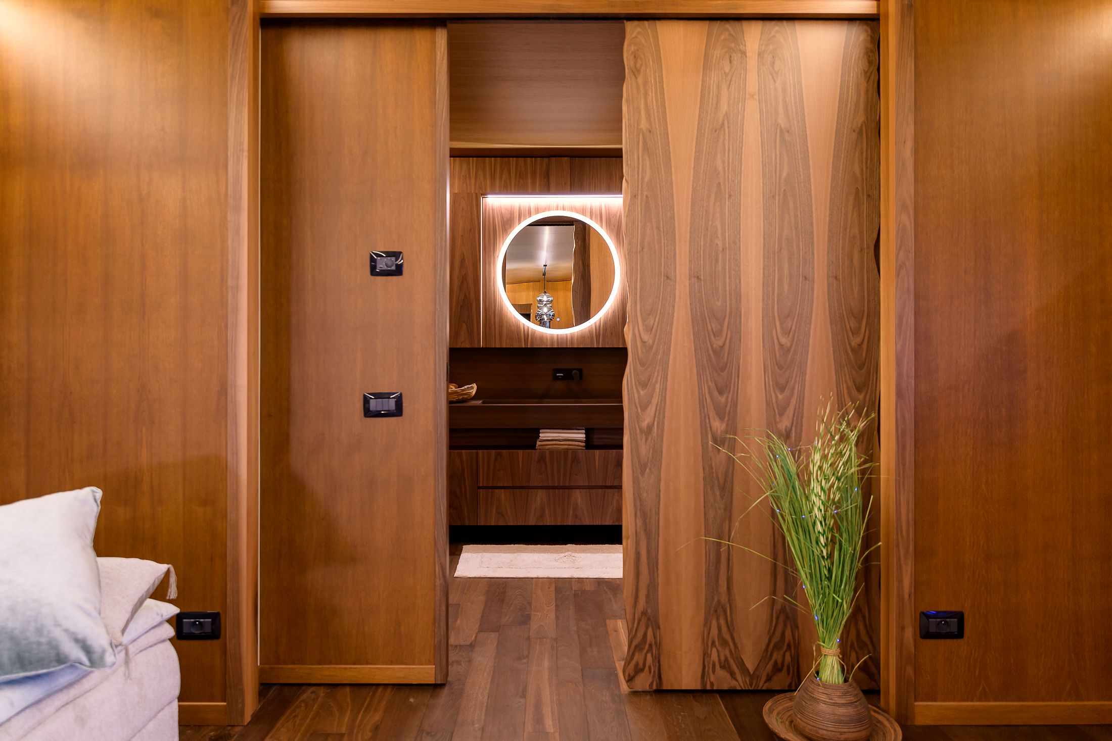 Corridoio interno di un living trailer con porte scorrevoli in legno e specchio retroilluminato