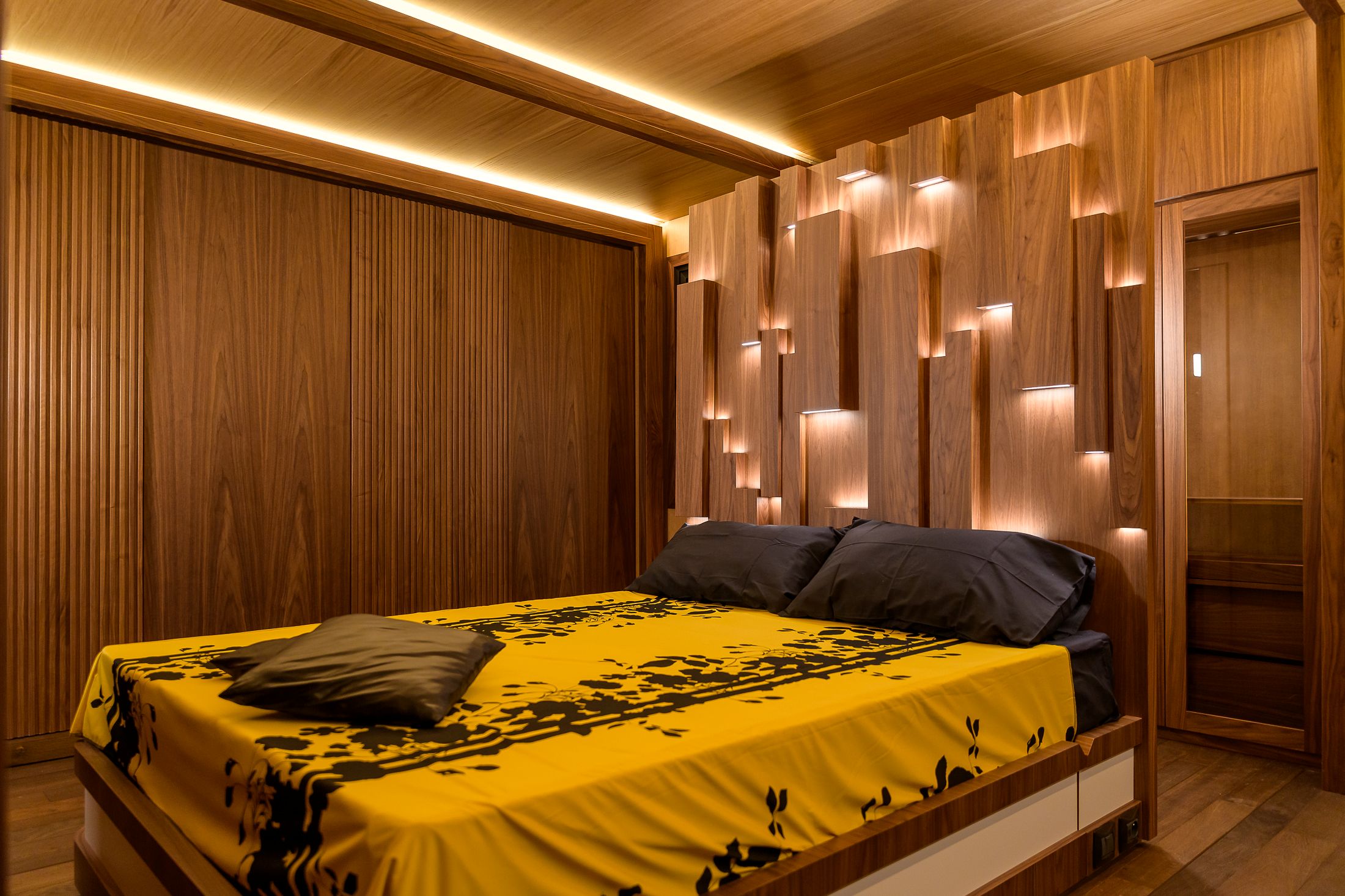 Camera da letto di un living trailer con testiera in legno scolpito e illuminazione scenografica
