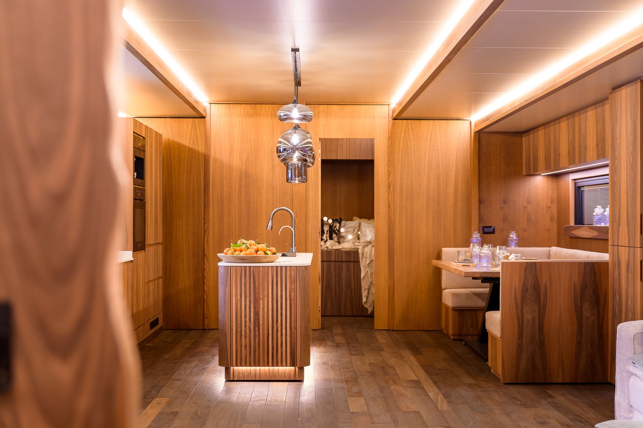 Cucina a isola e zona pranzo di un living trailer rifinito in legno
